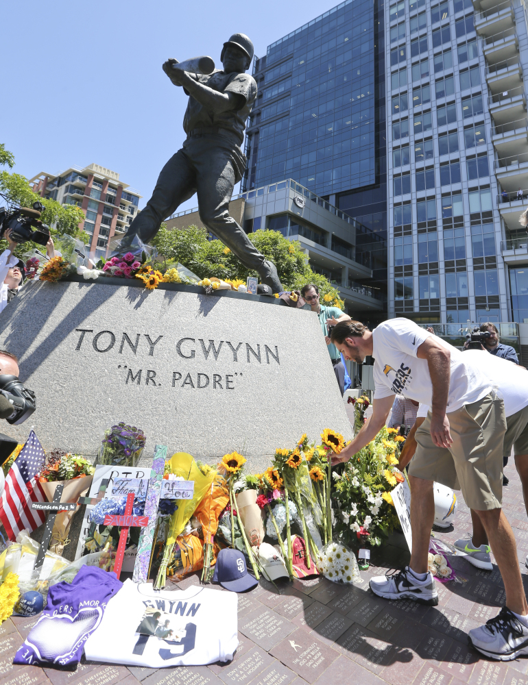 Members of the San Diego Chargers place flowers at the base of the Tony Gwynn “Mr. Padre” statue, Monday, June 16, 2014, in San Diego. Gwynn, an eight time National League batting champion with the San Diego Padres and a member of Baseball Hall of Fame, died Monday from cancer. He was 54.