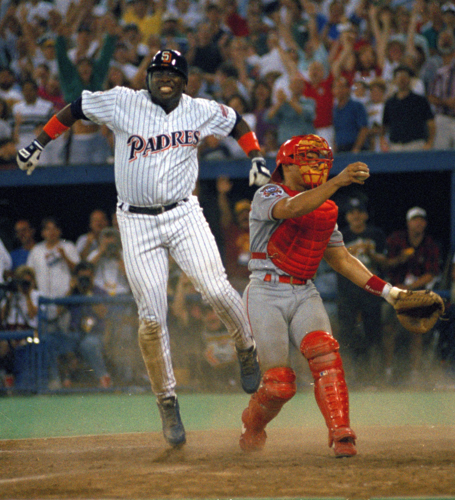 In this July 12, 1994, photo, San Diego Padres’ Tony Gwynn leaps in the air after sliding home safely to score the winning run as Texas Rangers catcher Ivan Rodriguez stands by in the 10th inning of the MLB All-Star Game at Pittsburgh’s Three Rivers Stadium.