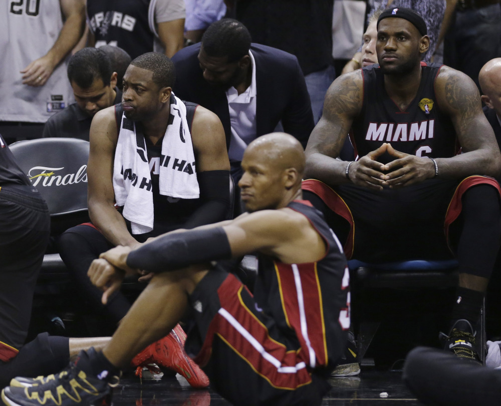 From left, Miami Heat guard Dwyane Wade, guard Ray Allen and forward LeBron James (6) sit on the bench in the final moments at Game 5 of the NBA basketball finals on Sunday, June 15, 2014, in San Antonio.