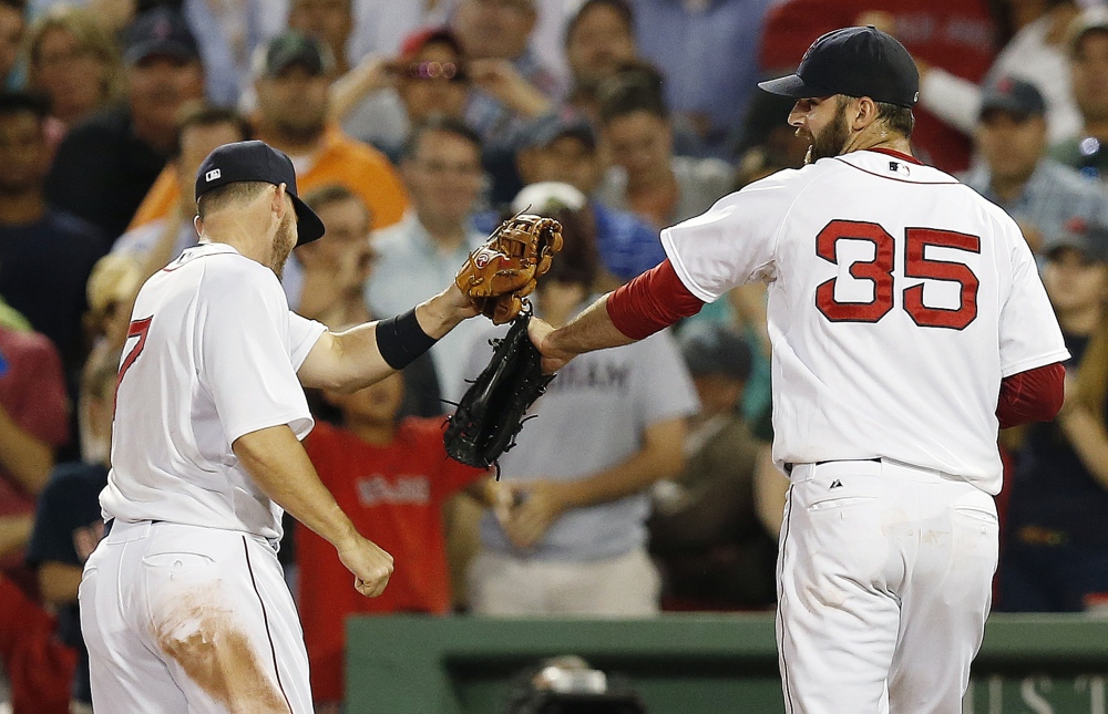 Boston Red Sox's Stephen Drew (7) taps gloves with Burke Badenhop (35) after Badenhop struck out Minnesota Twins' Brian Dozier to retire the side with bases loaded during the eighth inning Monday.