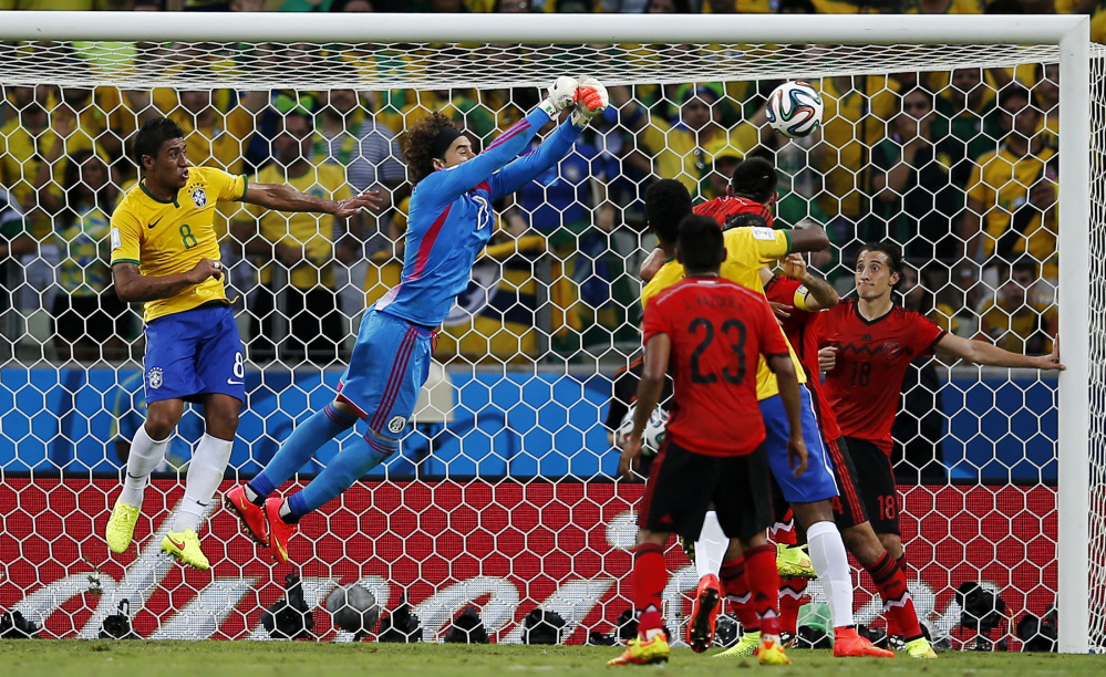 Brazil’s Paulinho (8) watches as Mexico’s goalkeeper Guillermo Ochoa punches the ball clear of the goal during the group A World Cup soccer match between Brazil and Mexico at the Arena Castelao in Fortaleza, Brazil, Tuesday, June 17, 2014.