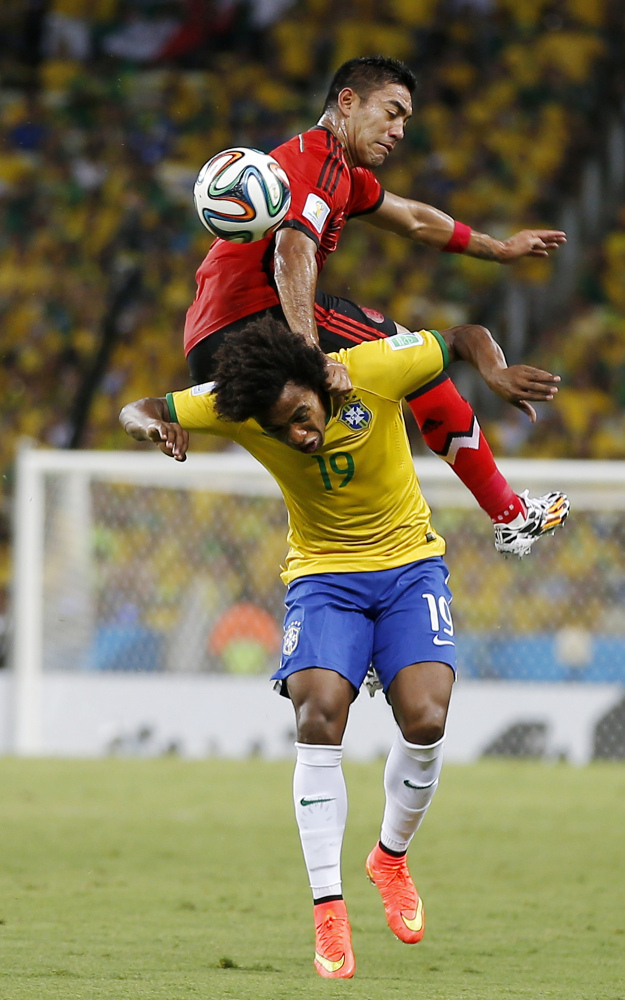 Mexico’s Marco Fabian flips over Brazil’s Willian while trying to head the ball during the group A World Cup soccer match between Brazil and Mexico.
