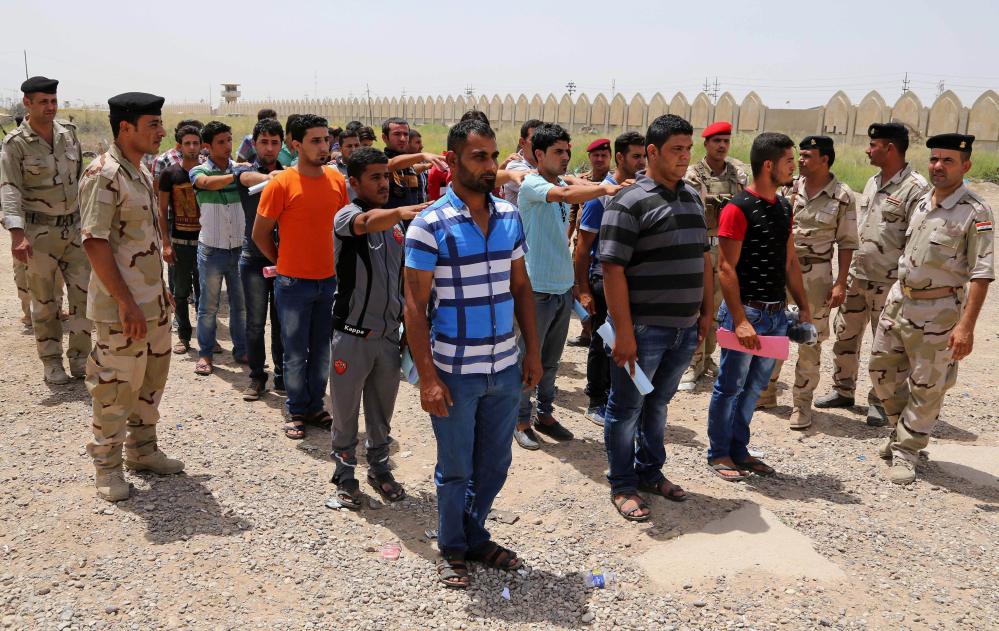 This June. 12, 2014 photo shows Iraqi men lining up outside of the main army recruiting center to volunteer for military service in Baghdad, Iraq, after authorities urged Iraqis to help battle insurgents. Iraq’s military has been deeply shaken by their humiliating collapse in the face of an onslaught by Islamic militants the past two weeks.