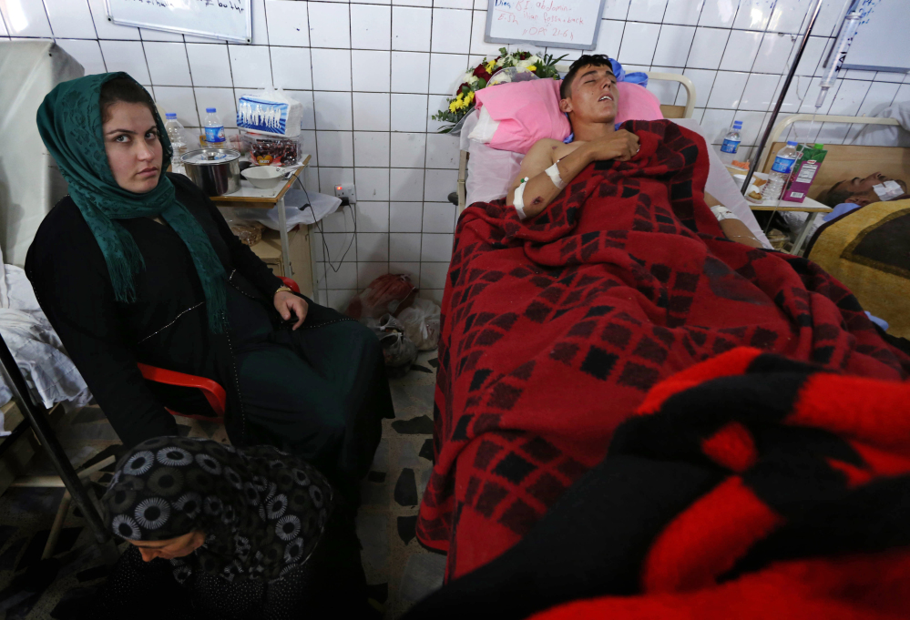 Relatives stand vigil for a Kurdish peshmerga fighter wounded in fighting with al-Qaida-inspired Sunni militants as he is treated in a hospital in Irbil, Iraq, on Wednesday.
