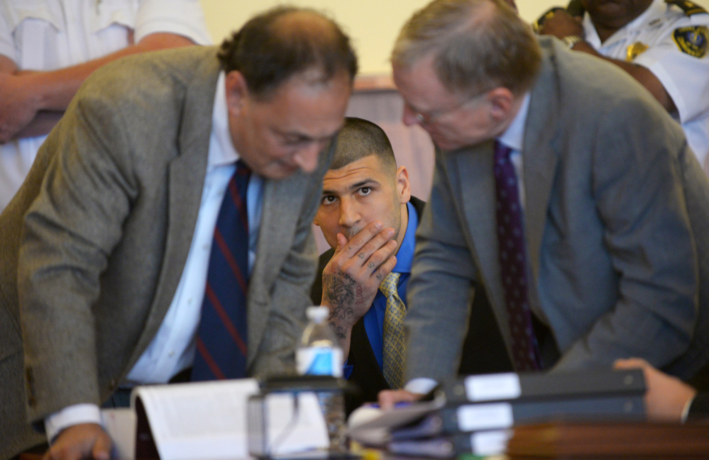 Former New England Patriots NFL football player Aaron Hernandez watches his defense attorneys James Sultan and Charles Rankin during a hearing at the Bristol County Superior Court House on Monday in Fall River, Mass.