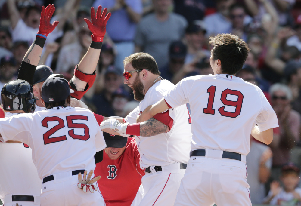 Boston Red Sox’s Mike Napoli, center, is congratulated by teammates after his game-winning, walk off home run against the Minnesota Twins during the 10th inning of a baseball game at Fenway Park in Boston, Wednesday, June 18, 2014. The Red Sox won 2-1 in 10 innings.