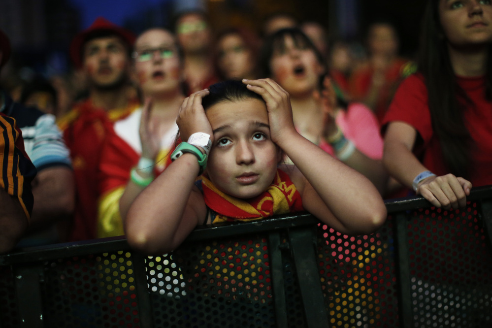 A Spanish soccer fan holds her head as she watches, on a giant display, the World Cup soccer match between Spain and Chile, in Madrid, Spain, Wednesday, June 18, 2014.