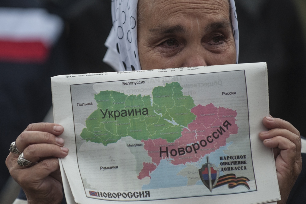 A woman holds a map showing Ukraine divided into two parts – the eastern part labeled Novorossia, or New Russia – during a rally in Donetsk, Ukraine, on Wednesday.