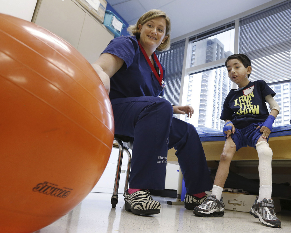 Physical therapist Katherine Hartigan works with Ihor Lakatosh, 11, at Shriners Hospital for Children in Boston last month. Ihor sustained burns in Ukraine in 2011. Neglect had caused his burned skin to contract, fusing his arm to his chest and leaving him unable to walk.