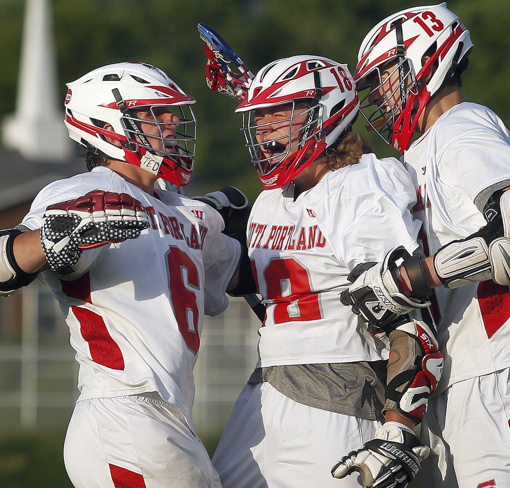 Thomas Leddy, center, of South Portland, got the tying goal with 6.9 seconds left. He celebrates with Duncan Preston, left, and Jack Fiorini. The Red Riots won their first regional title in boys’ lacrosse.