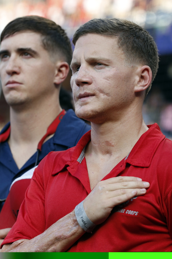 Retired U.S. Marine Cpl. William “Kyle” Carpenter, right, stands during the National Anthem before a baseball game between the Washington Nationals and the Houston Astros in Washington on Tuesday.