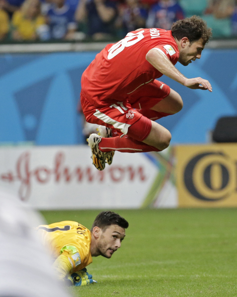 Switzerland’s Admir Mehmedi leaps over France’s goalkeeper Hugo Lloris after taking a shot on goal during the group E World Cup soccer match between Switzerland and France in Salvador, Brazil, on Friday.