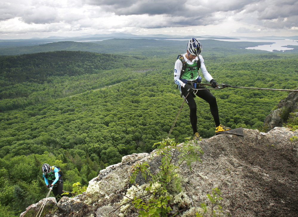 It’s not all downhill from here, but on the first day of the 200-mile, four-day wilderness adventure in the Moosehead Lake region, Ryan VanGorder, right, of team Dart Nuun began his rappel down Little Kineo Mountain, where other grueling tests were waiting at the base.