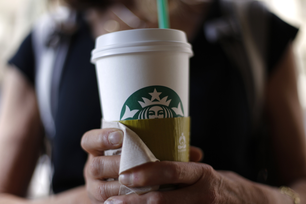 A woman holds a coffee drink outside a Starbucks in downtown Chicago. Starbucks is raising prices on some of its drinks by 5 cents to 20 cents starting next week, and customers can soon expect to pay $1 more for the packaged coffee it sells in supermarkets. Prices for medium and large brewed coffees, which are known as Grande and Venti, respectively, will go up between 10 cents and 15 cents in most U.S. markets, the company said.