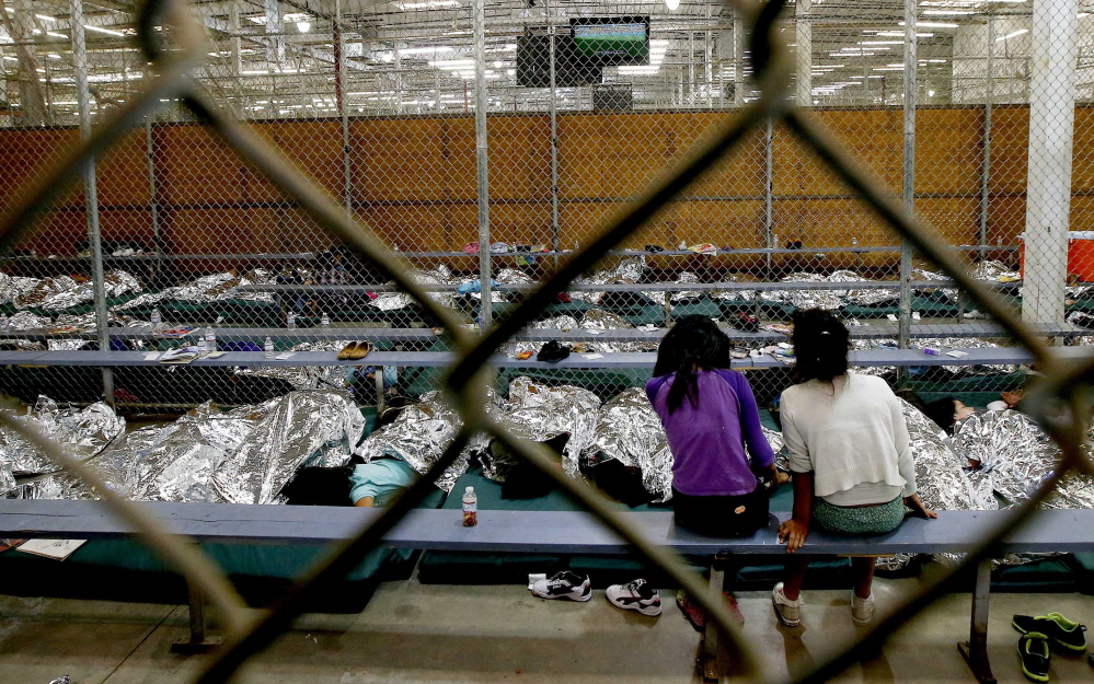 Two girls watch a World Cup soccer match on a television with other children lying under reflective blankets on Wednesday in their holding area at the U.S. Customs and Border Protection Nogales Placement Center in Nogales, Ariz.