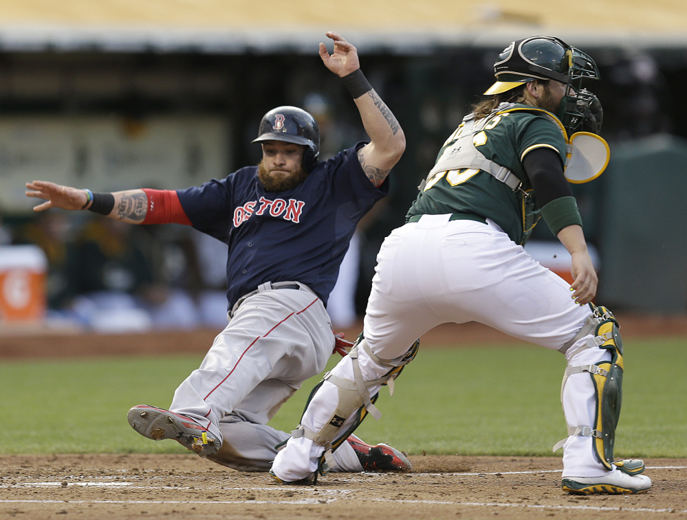 Boston’s Jonny Gomes slides past Oakland catcher Derek Norris to score in the second inning Friday in Oakland, Calif. Gomes scored on a single by Jackie Bradley Jr. The Red Sox lost 4-3.
