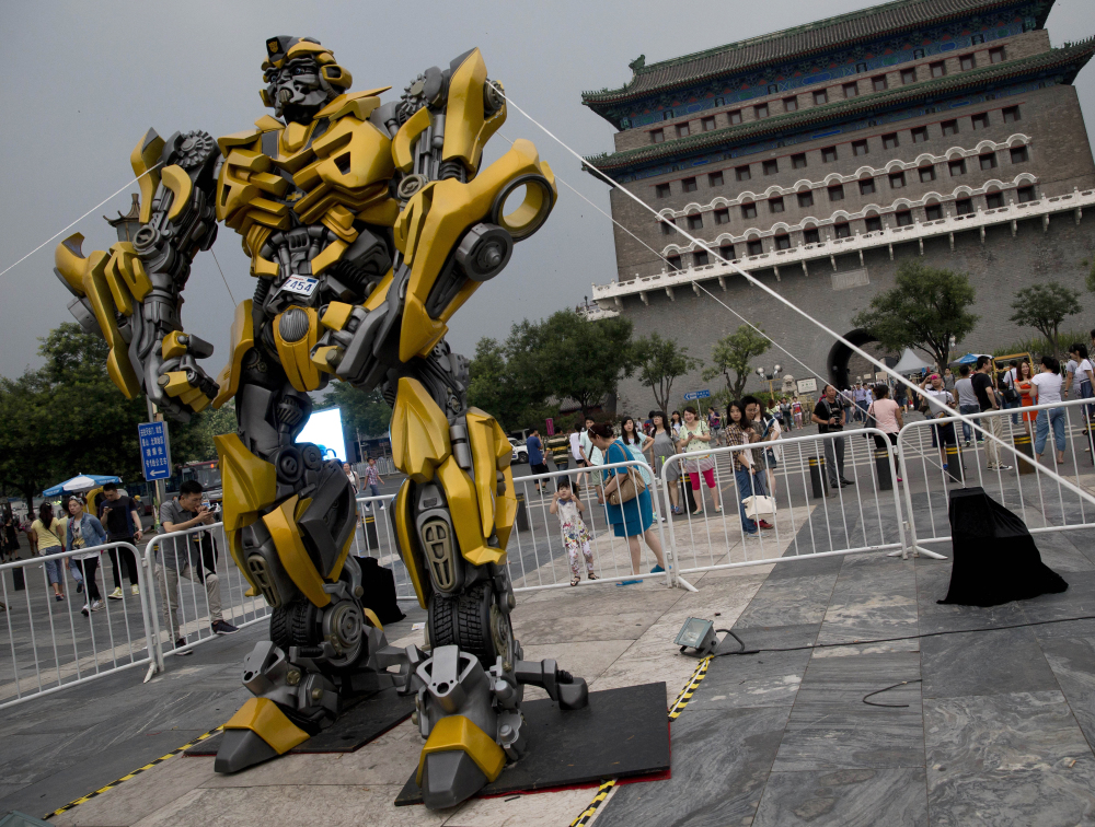 A child looks at a replica model of Transformers character Bumblebee in Beijing, as part of a promotion of the movie “Transformers: Age of Extinction” on Saturday.