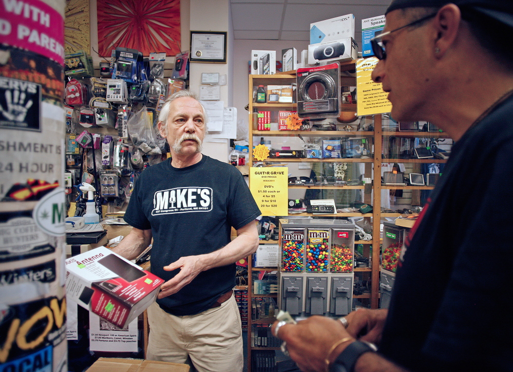 Mike Fink, owner of the Guitar Grave pawnshop in downtown Portland, sells a television antenna to Craig Campbell. Amelia Kunhardt/Staff Photographer