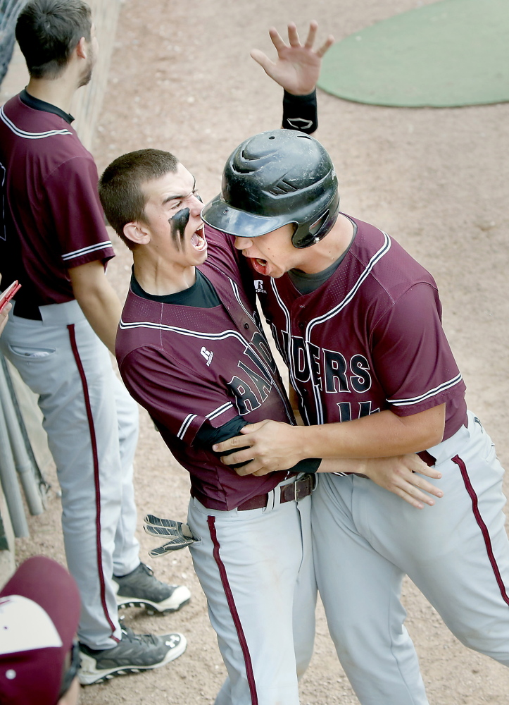 Colin Pineo, right, of Washington Academy is congratulated by teammate Kyle Taylor after Pineo scored the Raiders’ third run in the first inning against Sacopee Valley during the Class C state championship game Saturday in Standish. Washington won, 7-1.