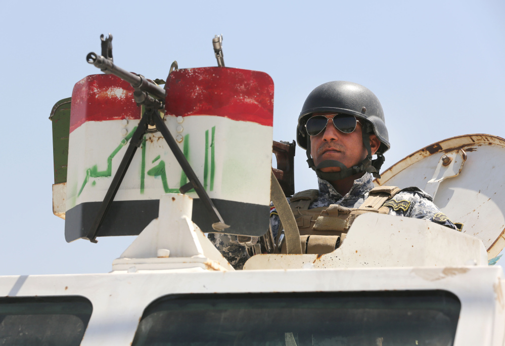 An Iraqi federal policeman standing on top an armored vehicle secures a checkpoint in Baghdad, Iraq, on Sunday. Sunni militants have seized another town in Iraq’s western Anbar province, the fourth to fall in two days, officials said Sunday, in what is shaping up to be a major offensive in one of Iraq’s most restive regions.
