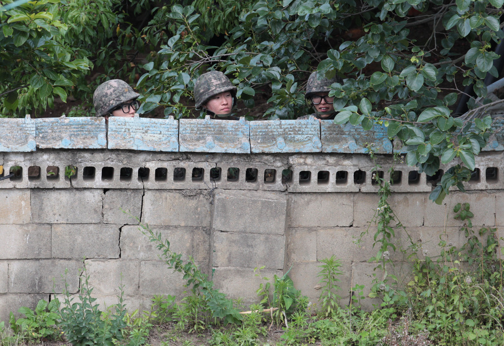 South Korean army soldiers hide behind a wall of a private house during a gunfight with a South Korean conscript soldier who is on the run after a shooting incident in Goseong, South Korea, on Sunday.
