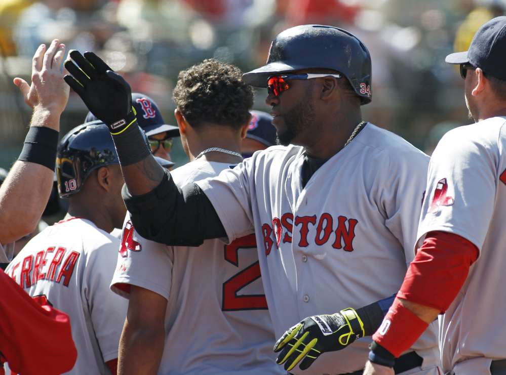 Boston Red Sox designated hitter David Ortiz is greeted at the dugout after hitting the game-winning home run against the Oakland Athletics in the 10th inning Sunday.