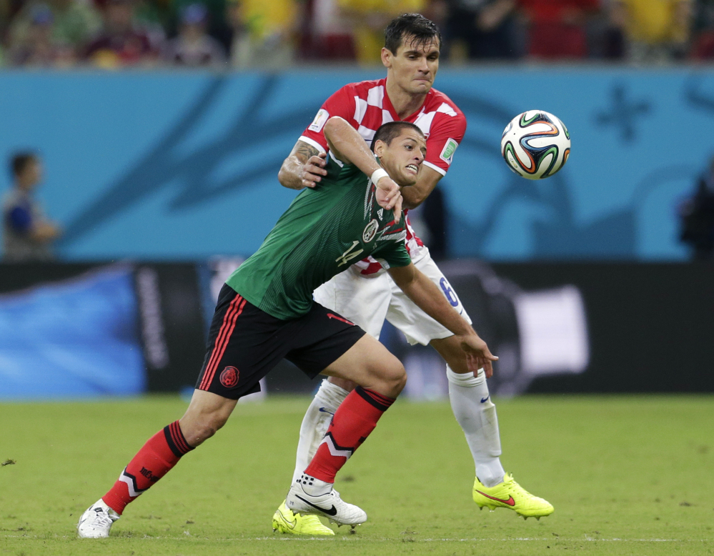 Mexico’s Javier Hernandez, front, is held back by Croatia’s Dejan Lovren during the group A World Cup soccer match.