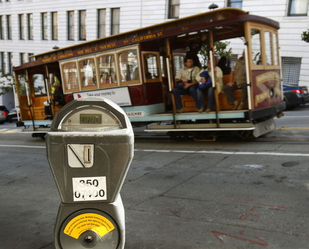 A cable car passes a parking meter near San Francisco’s financial district. San Francisco City Attorney Dennis Herrera on Monday issued a cease-and-desist demand to a mobile app called Monkey Parking, which allows people to auction off public parking spaces that they’re using to other nearby drivers.