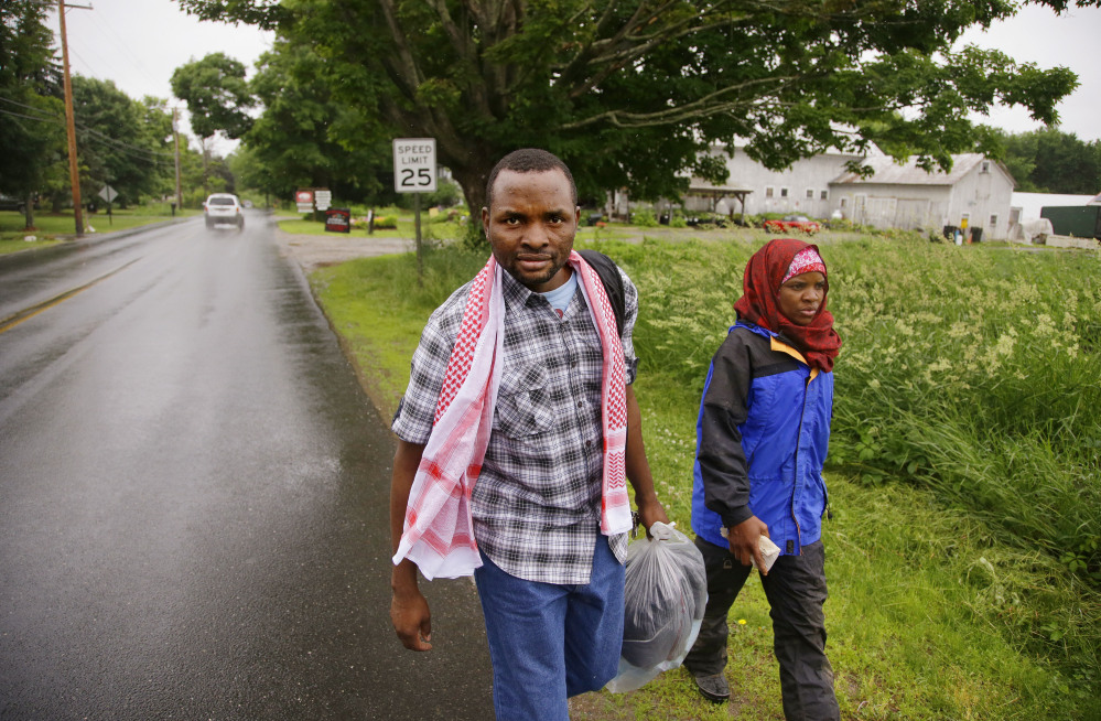 Somali refugee Adan Abdi, left, walks with his wife, Fatumo Mohamed, back to her car after a rainy afternoon forced an early end to her work day as a farm hand on Red Fire Farm in Montague, Mass. Abdi works the graveyard shift in the maintenance department of a local hospital. The couple has three children.