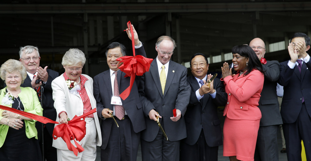 In this May 28, 2014 photo provided by the Alabama Governor’s office, Gov. Robert Bentley, flanked by Quingmin Li, Consul General China, Houston office, left, and Golden Dragon Copper USA Chairman Changjie Li, pose for photos with company, state and local officials at a ribbon cutting ceremony during the grand opening of the company’s copper tubing plant in Pine Hill, Ala.
