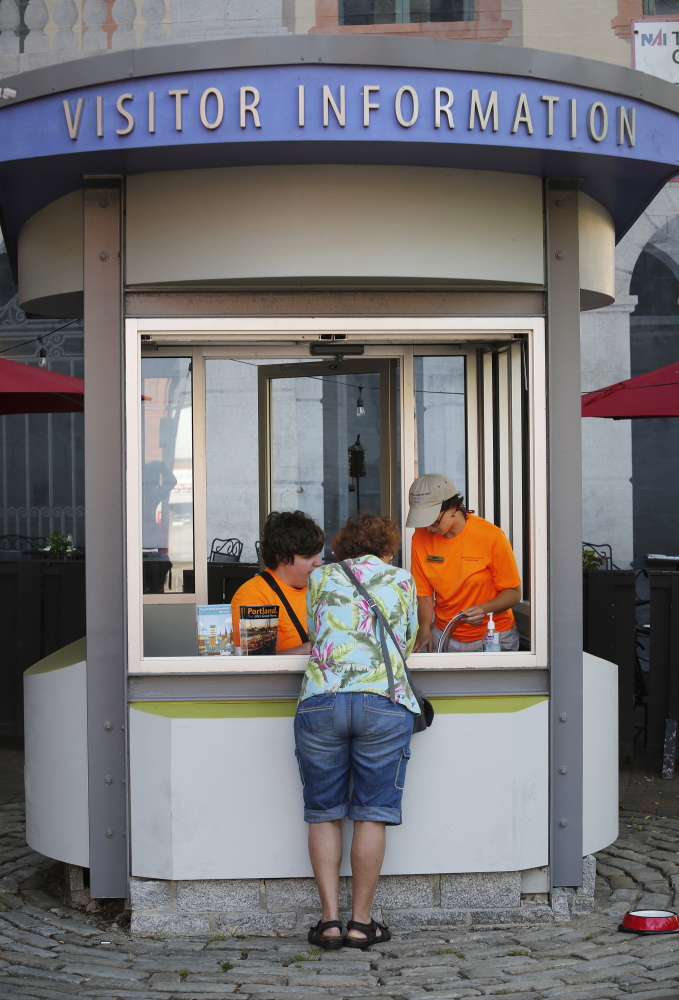 Robert Chason, left, and Becky Wartell help a visitor at the Portland Downtown District information kiosk at Tommy’s Park on Monday.