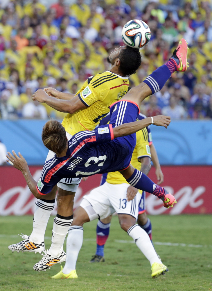 Japan’s Yoshito Okubo shoots next to Colombia’s Carlos Valdes during the group C World Cup soccer match between Japan and Colombia.