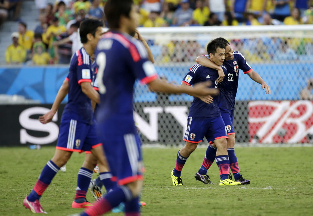 Japan’s Shinji Okazaki second from right, celebrates with teammate Japan’s Maya Yoshida after scoring during the group C World Cup soccer match between Japan and Colombia.