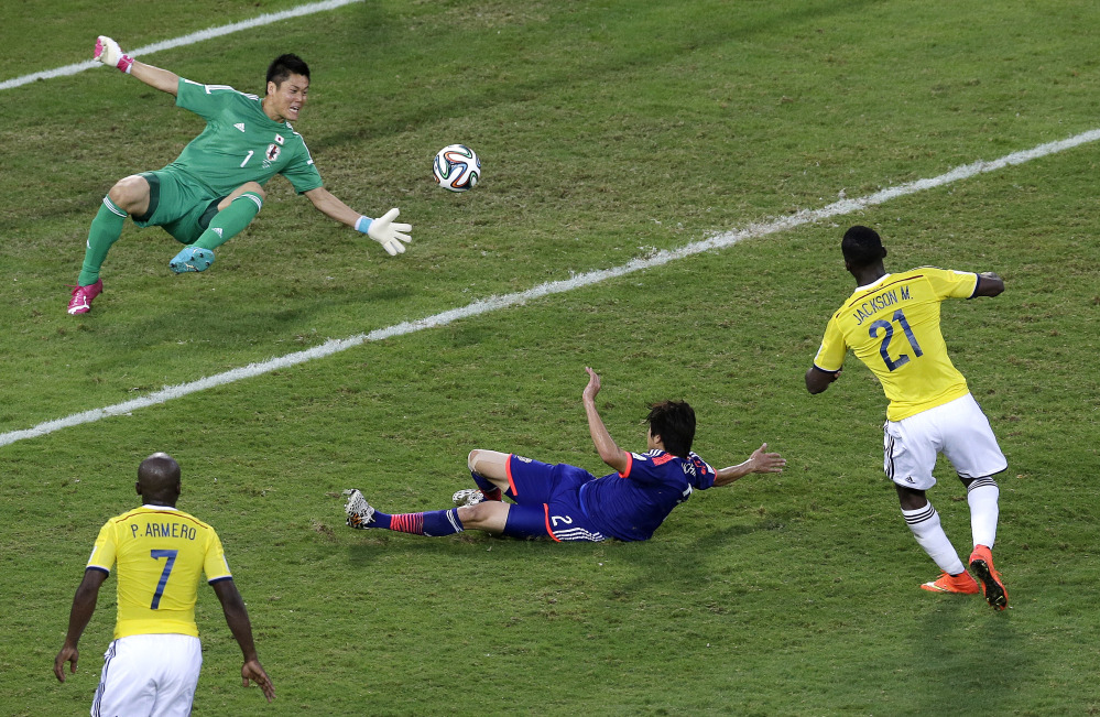 Colombia forward Jackson Martinez, right, scores past Japan defender Atsuto Uchida and goalkeeper Eiji Kawashima during the second half of a group C World Cup soccer match in Cuiaba, Brazil, Tuesday, June 24, 2014.