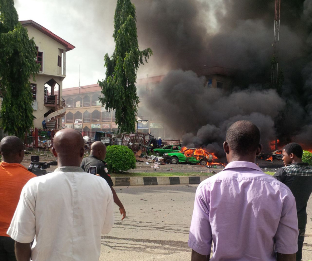 People watch as smoke fills the sky after an explosion rocked a shopping mall Wednesday in Abuja, Nigeria.