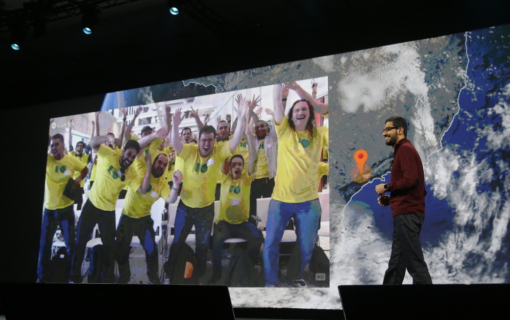 Sundar Pichai, right, Google’s senior vice president who oversees Android  and Chrome software divisions, smiles as a group watching live from Brazil is projected on the screen during the Google I/O 2014 keynote presentation in San Francisco on Wednesday.
