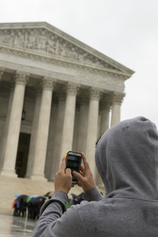 A visitor uses a cellphone to photograph the Supreme Court in Washington. The court rules that police need warrants to search cellphones.