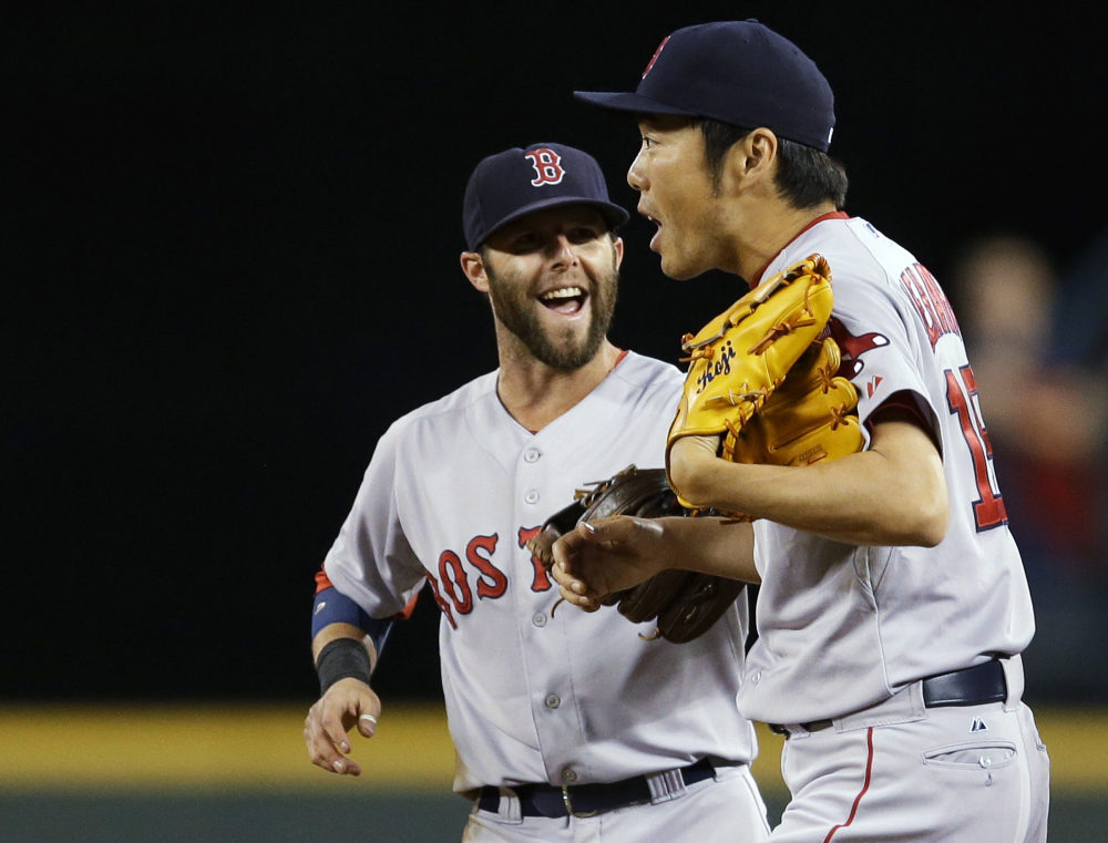Boston Red Sox closer Koji Uehara, right, is greeted by Dustin Pedroia after the Red Sox defeated the Seattle Mariners 5-4 Wednesday in Seattle.