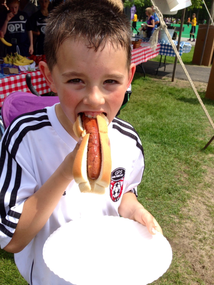 Sam Gagner, 10, of Berwick bites into a Pineland Farms hot dog at a Brunswick soccer tournament. His review: “It’s so good it doesn’t even need ketchup.”