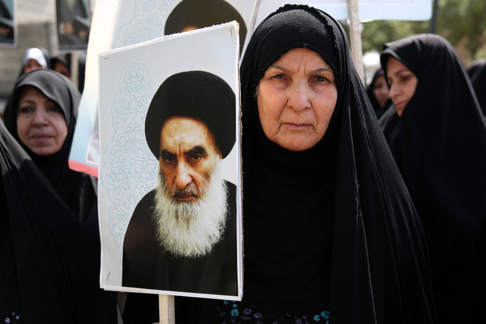 An Iraqi woman living in Iran holds a poster of the Grand Ayatollah Ali al-Sistani, Iraq’s top Shiite cleric, in a demonstration against Sunni militants of the al-Qaida-inspired Islamic State of Iraq and the Levant, or ISIL, and to support Ayatollah al-Sistani, in Tehran, Iran. Prominent Shiite leaders pushed Thursday for the removal of Iraqi Prime Minister Nouri al-Maliki.