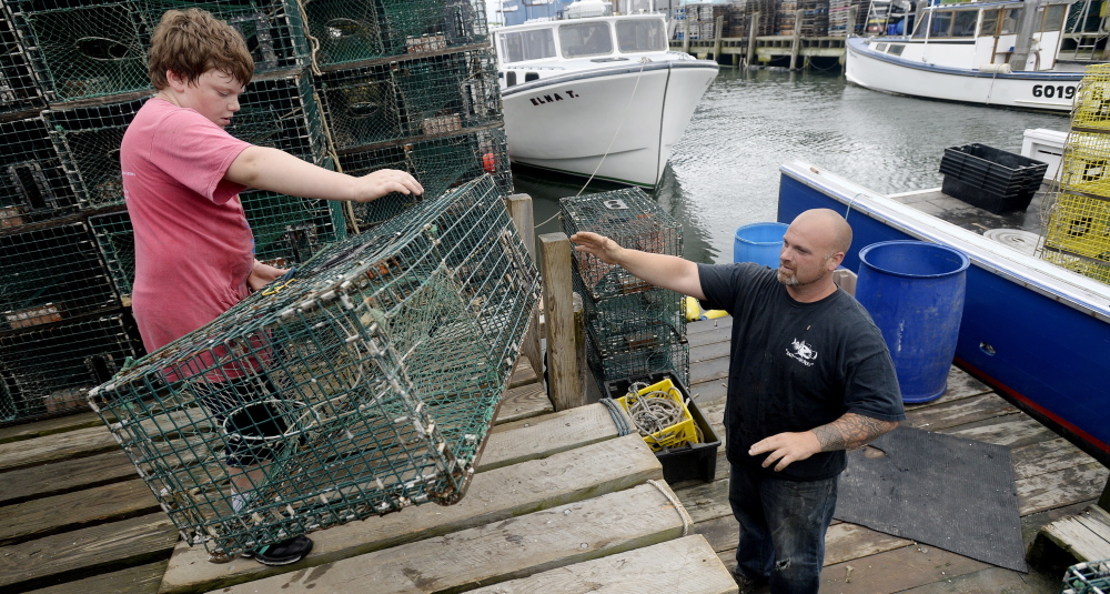 Rocco Mancini, 9, passes a lobster trap to his father, Nick Mancini of Falmouth, as they prepare for a trip to sea at Widgery Wharf in Portland. Last year, 125.9 million pounds of lobster were harvested in Maine.