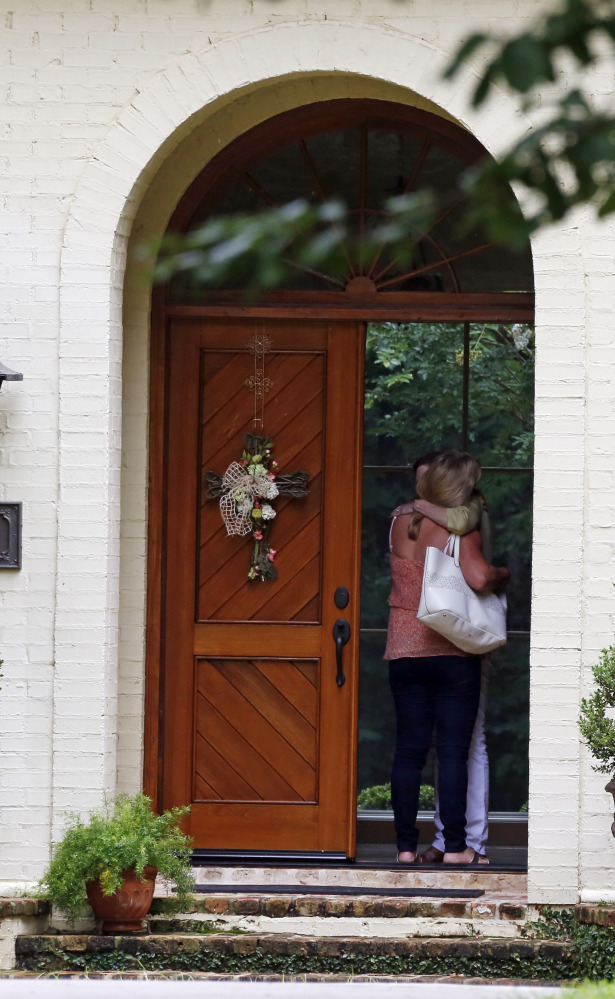 A visitor is hugged at the front door of the home of tea party official Mark Mayfield on Friday in Ridgeland, Miss., where he was found dead.