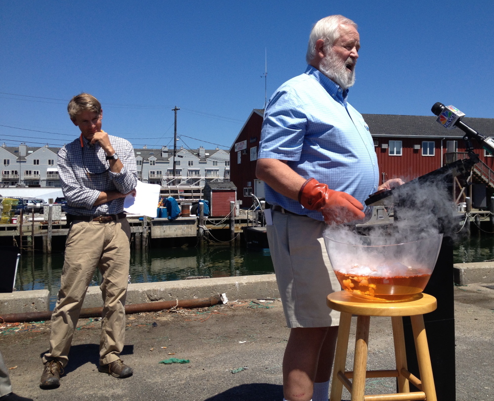 Eric Horne, left, an oyster farmer from Freeport, takes in a demonstration by Casco Baykeeper Joe Payne, who uses chemicals to show the acidity levels in a bowl of seawater during a news conference Friday on the Portland waterfront. A new state panel will study the impact of ocean acidification on the shellfish industry.