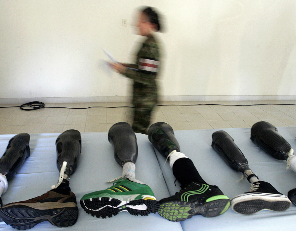 A member of the Colombian army walks past prosthetic limbs to be delivered to victims of land mines, in Medellin in 2011. File Photo/The Associated Press