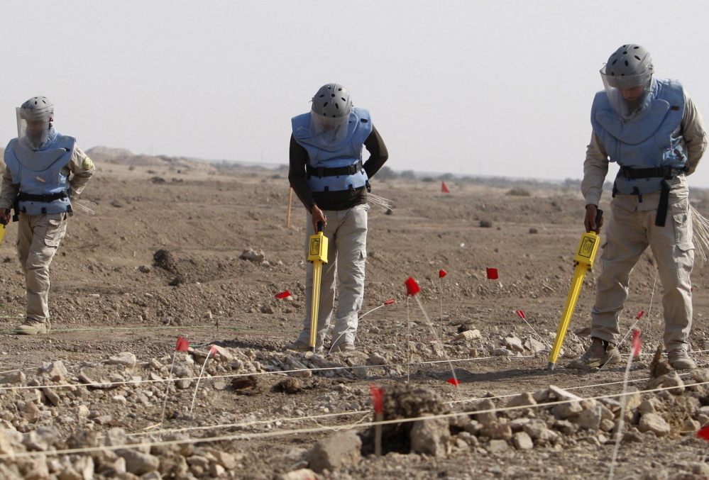 Above, members of the Iraqi Mine and Unexploded Ordnance Clearance Organization work to find land mines in the Shatt-al-Arab district, in Iraq’s southern city of Basra, in 2012. File Photo/The Associated Press