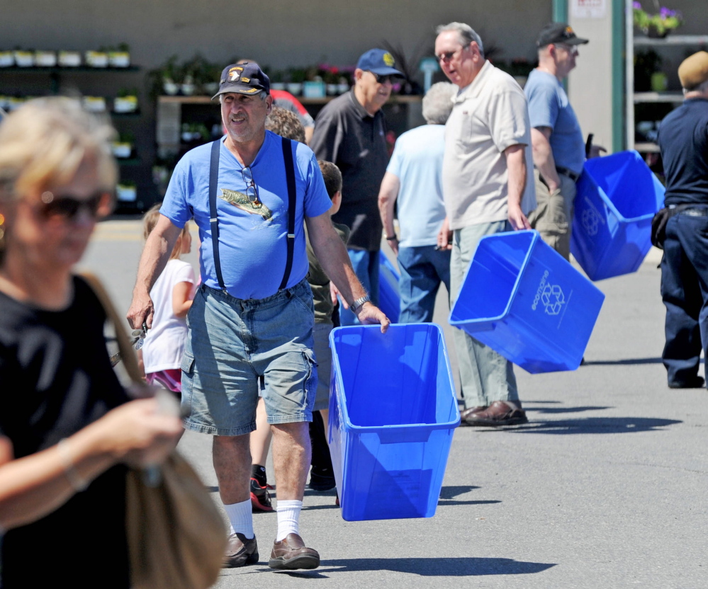 People make their way back to their vehicles with free recycling bins from Ecomaine at Elm Plaza in Waterville on Friday.