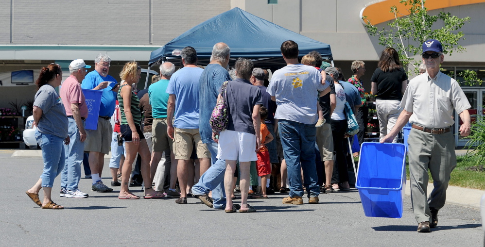 Louis DeRosby, far right, walks back to his car after picking up a free recycling bin from Ecomaine at Elm Plaza in Waterville on Friday. Ecomaine, the company running Waterville’s new recycling program distributed 100 recycling bins to residents.