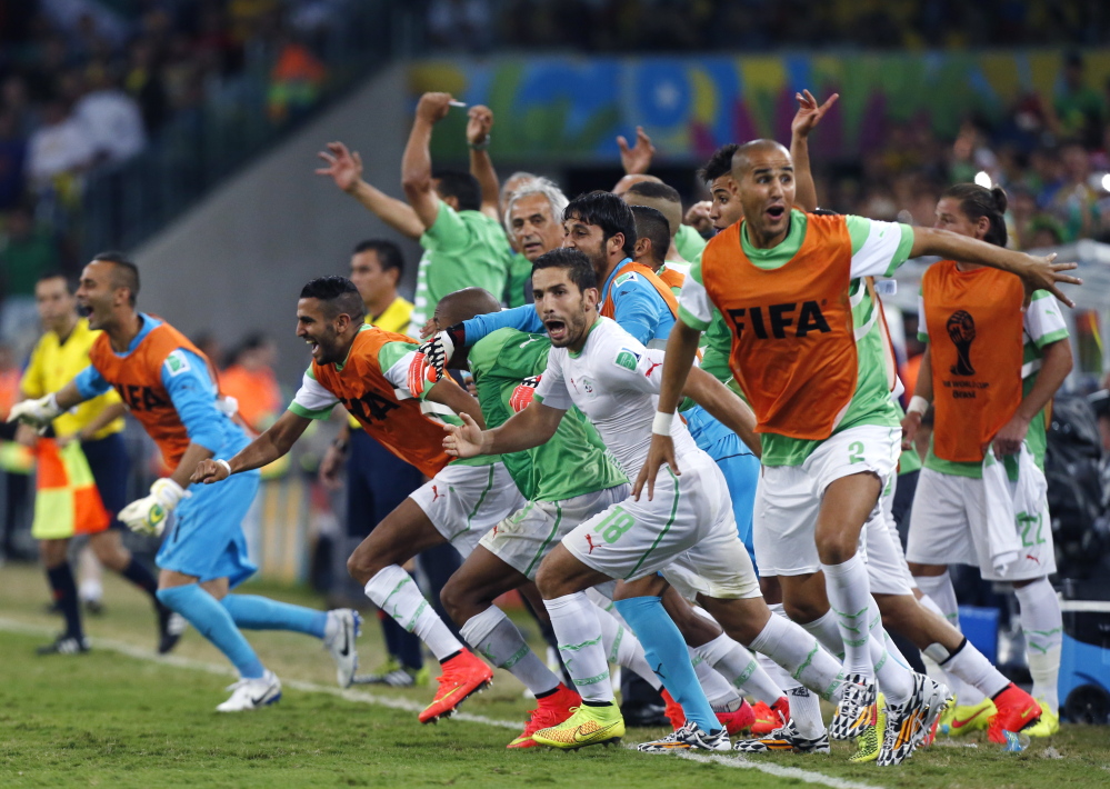 Algeria’s bench players run onto the field Thursday in Curitiba, Brazil, to celebrate after their 1-1 draw with Russia allowed Algeria to qualify for the knockout stage. Coupled with Nigeria’s earlier qualification, the World Cup has two African teams in the Round of 16 for the first time.