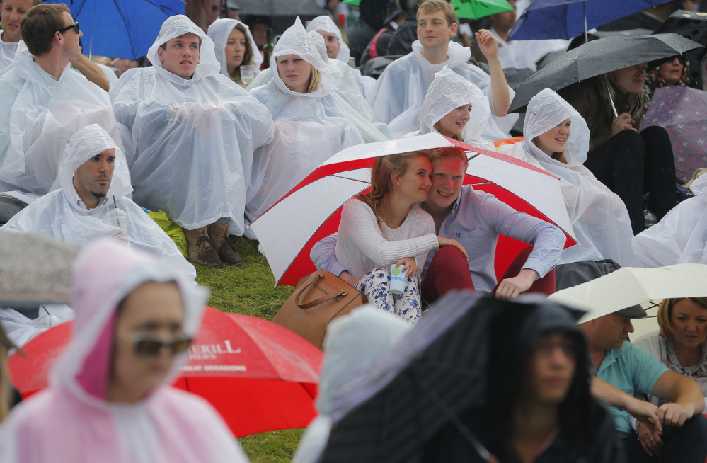 Spectators wear raincoats or sit under umbrellas during rain at the All England Lawn Tennis Championships
Pavel Golovkin/The Associated Press