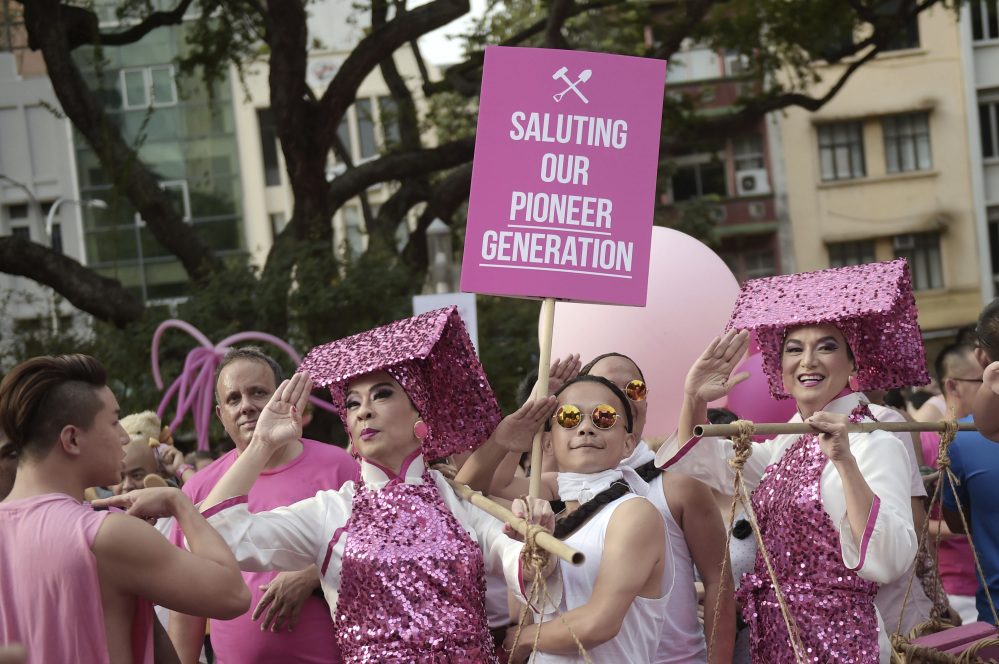 Gay activists dressed as female construction workers or Samsui Women and laborers from the colonial period pose in mock salute at Saturday’s rally in Singapore.